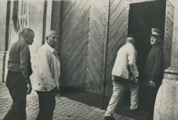 Mehrere Personen gehen auf eine Tür zu, vor der ein Mann in Uniform steht
