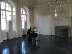 Markus Thulin sitzt an einem Schreibtisch allein im Kaisersaal der Abtei Brauweiler und kommuniziert über einen Laptop mit einer Schulklasse.