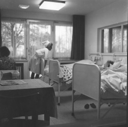 Auf dem Bild ist eine Krankenschwester an einem Krankenbett zu sehen
